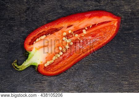 Half Of The Fresh Red Bell Pepper Cut Lengthwise On The Dark Surface, Top View