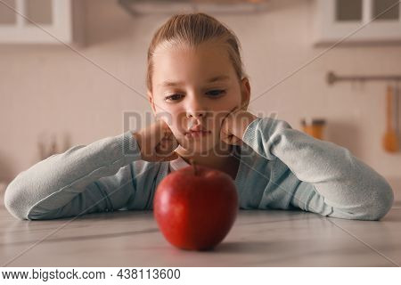 Cute Little Girl Refusing To Eat Apple In Kitchen