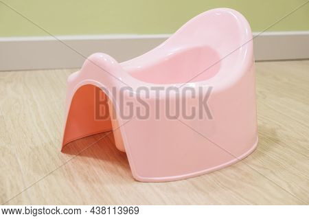 Pink Plastic Baby Potty Is On The Floor Of The Apartment. Toilet Training Chamber Pot For Small Chil