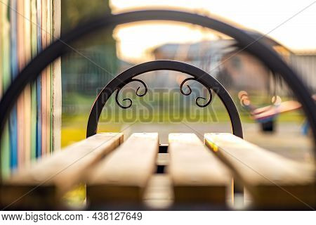 Closeup Of Wooden Park Bench With Metal Handgrip Outdoors.