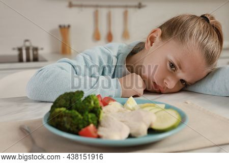 Cute Little Girl Refusing To Eat Dinner In Kitchen