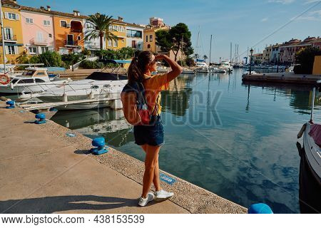 Woman Traveler Stands On Pier With Yachts And Boats At Beautiful Harbor Of Port Saplaya Near Valenci