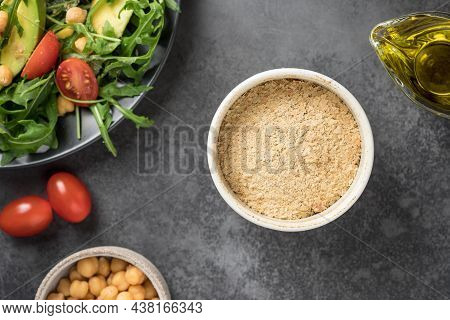 Nutritional Yeast Flakes In Ceramic Bowl On Dark Table. Dietary Supplement. Plant-based Food Concept