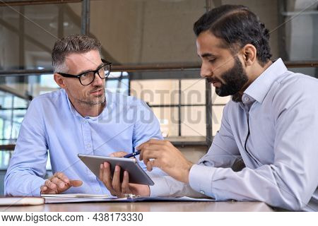 Caucasian And Indian Businessmen Ceo Negotiating At Table Meeting Using Holding Tablet Device Comput