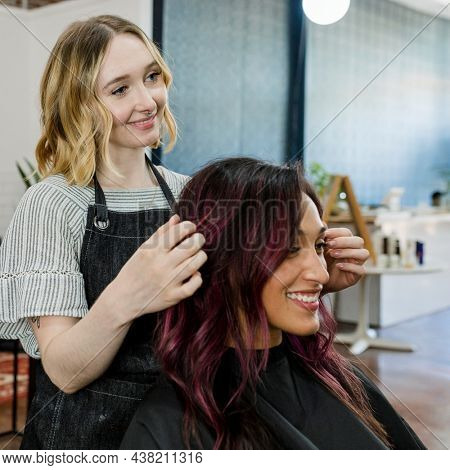 Hairstylist giving a finishing touch to customer at a beauty salon
