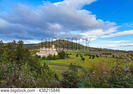 Magnificent Italy. Tuscany. The magnificent snow-white abbey of Sant Antimo among green grassy hills and slender cypress trees. Wonderful medieval architecture. 