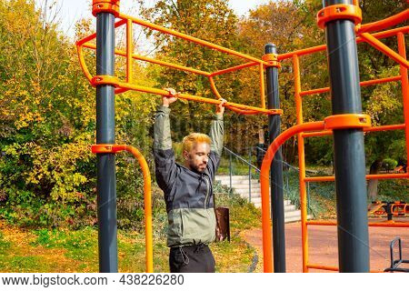 Men's Training On The Horizontal Bars In The Autumn Park. Training At The Open Air Sprorts Ground.