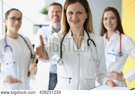 Friendly Young Woman Doctor Stretches Out Her Hand, Close-up. Consilium, Medical Staff Of The Clinic