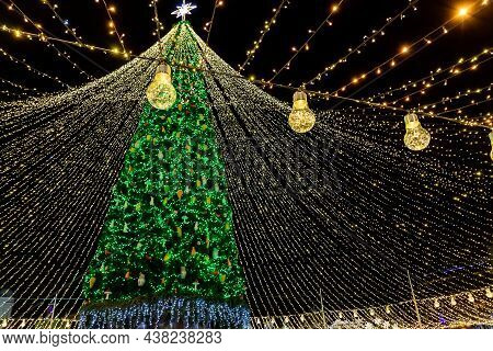 Beautiful Scenic Decorated Christmas Tree With Decorations And Illuminated By Light Garlands Against