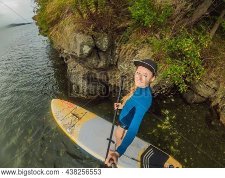 Young Women Having Fun Stand Up Paddling In The Sea. Sup. Red Hair Girl Training On Paddle Board Nea