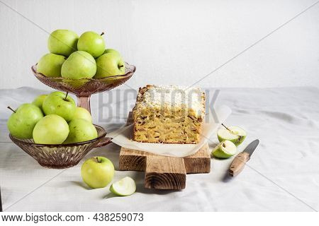 Apple And Coconut Oaf Cake On Wooden Cutting Board And Apples In A Vase. Copy Space