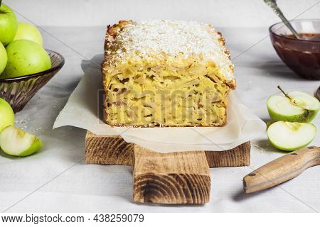 Apple And Coconut Oaf Cake On Wooden Cutting Board And Apples In A Vase