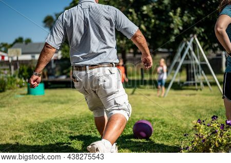 Playing Kickball With Grandpa In The Backyard