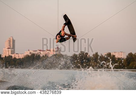 Athletic Strong Guy Holds Rope And Energetically Jumping And Flip With Wakeboard.