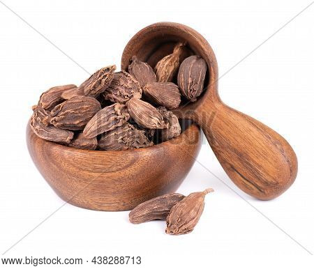 Heap Of Black Cardamom Pods In Wooden Bowl And Spoon, Isolated On White Background. Black Cardamon S