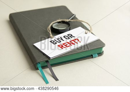 On The Notebook Is A Magnifying Glass And Paper Card With The Inscription Buy Or Rent