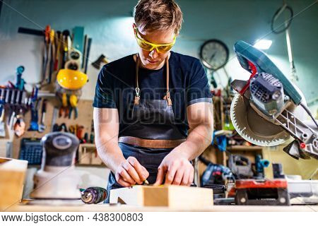 Portrait Of Handsome Carpenter Working With Plank In Workshop