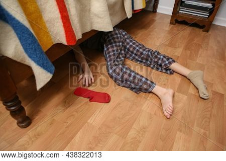 Young boy searching for his lost sock under the bed