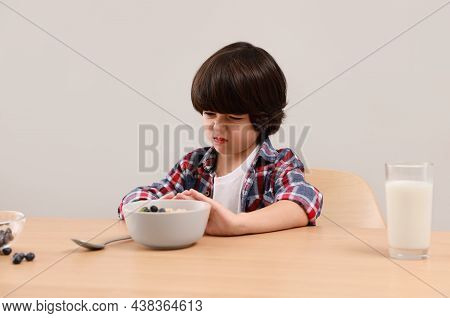 Cute Little Boy Refusing To Eat His Breakfast At Table On Grey Background
