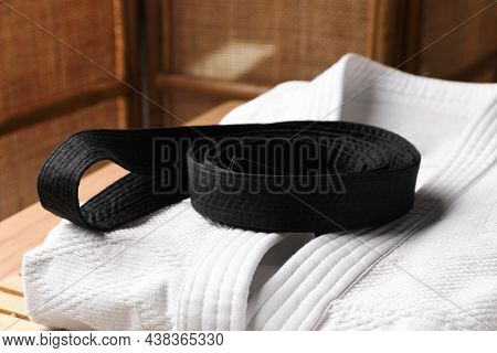 Martial Arts Uniform With Black Belt On Table Indoors, Closeup