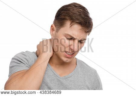 Unhappy Millennial Caucasian Attractive Guy Presses Hands To Sore Spot And Suffers From Neck Pain