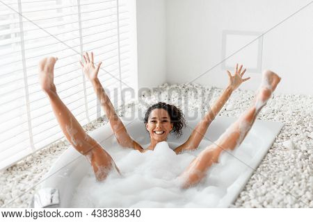 Silly Young Woman Having Fun In Bubble Bath, Raising Her Arms And Legs Up, Being Silly And Playful A