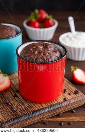 Chocolate Mug Cake With Whipped Cream And Fresh Berries On A Dark Wooden Background. Cupcake Cooked 