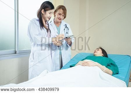 Caucasian Senior Woman Doctor Teach Asian Medical Student By Bedside Teaching Technique To Diagnosis