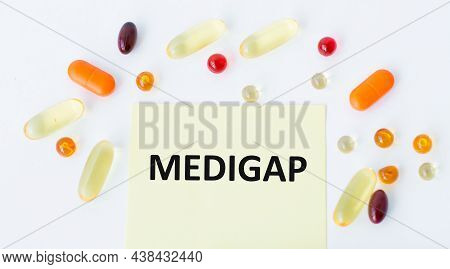 A Card With The Text Medigap On A White Background Colored Pills Are Scattered Nearby