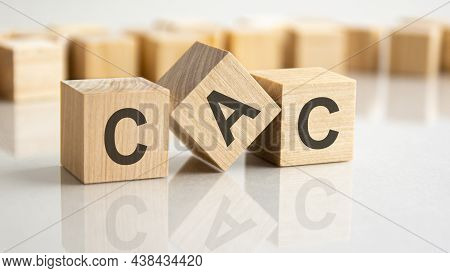 Three Wooden Blocks With The Letters Cac On The Bright Surface Of A Gray Table. The Inscription On T