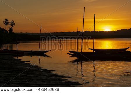 Silhouette At Sunset Of Canoes Docked In The Grandiose Paraguacu River.