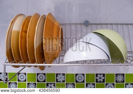 Closeup Of The Cleaned Dish And Blow Are Drying On The Stainless Dish Drainer Near The Kitchen Wall,