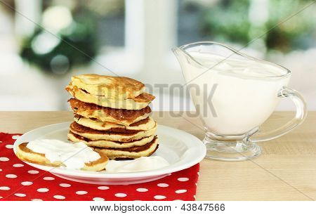 หวาน pancakes บนแผ่น ด้วยครีมเปรี้ยวบนโต๊ะในห้องครัว