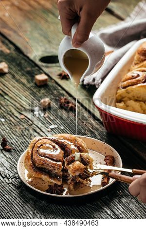 Sinnabon Buns Rolls. Woman's Hand Spreading Vanilla Cream.