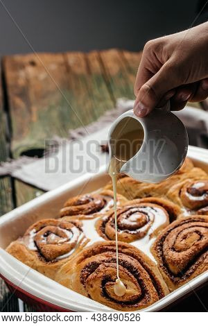 Sinnabon Buns Rolls. Woman's Hand Spreading Vanilla Cream.