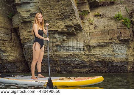 Young Women Having Fun Stand Up Paddling In The Sea. Sup. Red Hair Girl Training On Paddle Board Nea