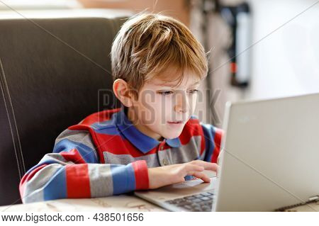 Happy Healthy Kid Boy With Glasses Making School Homework At Home With Notebook. Interested Child Wr