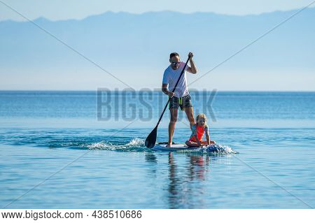 Father And Daughter Riding Sup Stand Up Paddle On Vacation.