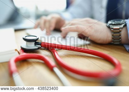 Close-up Of Medical Equipment Red Stethoscope On Workplace. Doctor Typing On Keyboard, Medical Build