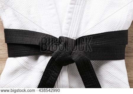 Martial Arts Uniform With Black Belt On White Wooden Background, Closeup