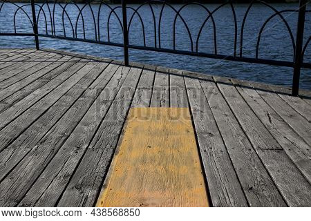 Low Angle View Of Wooden Deck And Metallic Railing By The Side Of A Lake