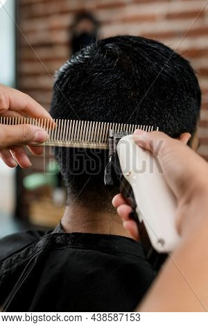 Hairdresser trimming hair of the customer at a barbershop