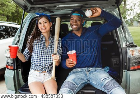 Friends sitting and drinking in the car boot at a tailgate party