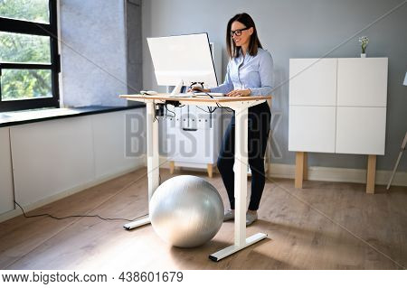 Woman Using Adjustable Height Standing Desk In Office For Good Posture