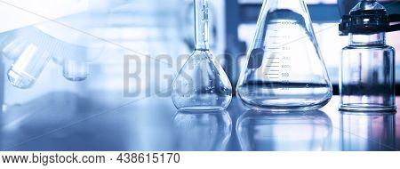 Conical And Volumetric Glass Flask With Microscope And Science Equipment In Chemistry Lab Purple Blu