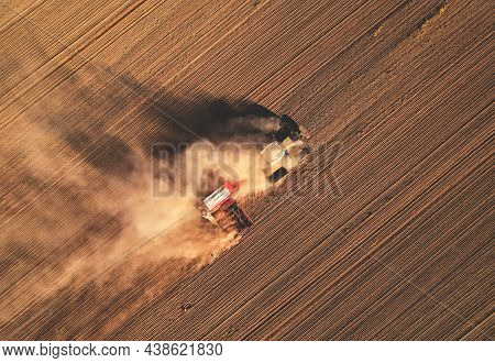 Agricultural Tractor Sowing Seed Onto At Field. Farming And Seeding Concept. Seeds Sowing In Farmers