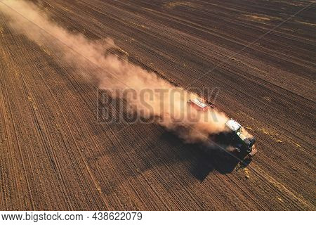 Agricultural Tractor Sowing Seed Onto At Field. Farming And Seeding Concept. Seeds Sowing In Farmers