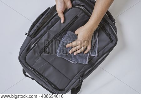 Cleaning Backpack With Washcloth. A Person Wipes Off Dirt Or Dust From The Outside Of The Bag. Wipin