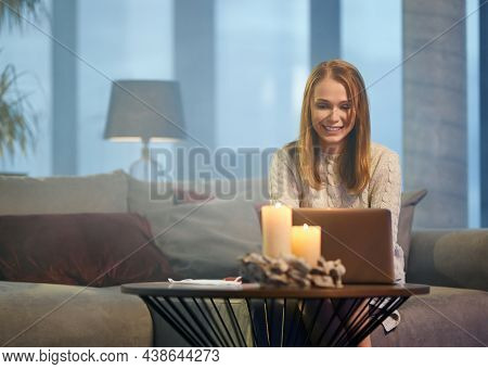 Smiling Caucasian Woman In Casual Wear Resting On Comfy Couch And Using Wireless Laptop. Pretty Youn