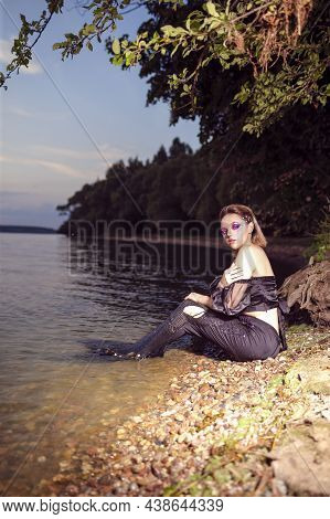 Mermaid Posing Near Sea Shore On Rocks While Wearing Artistic Makeup With Facial Strassses And Black